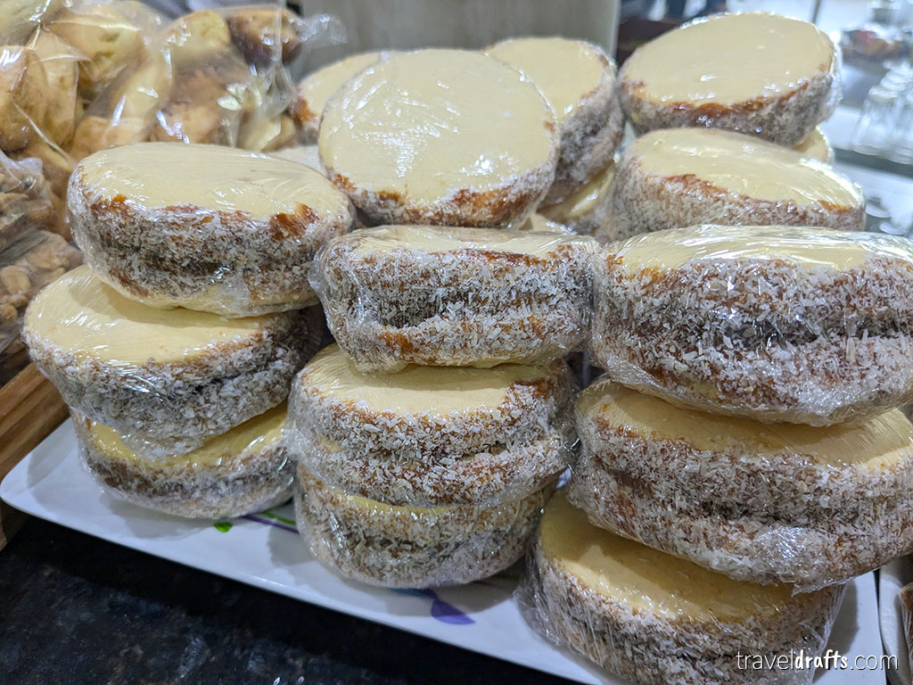 A stack of round desserts covered in shredded coconut and topped with cream, each individually wrapped and arranged on a platter—an inviting example of Paraguayan cuisine to try if you're wondering what to eat in Paraguay.